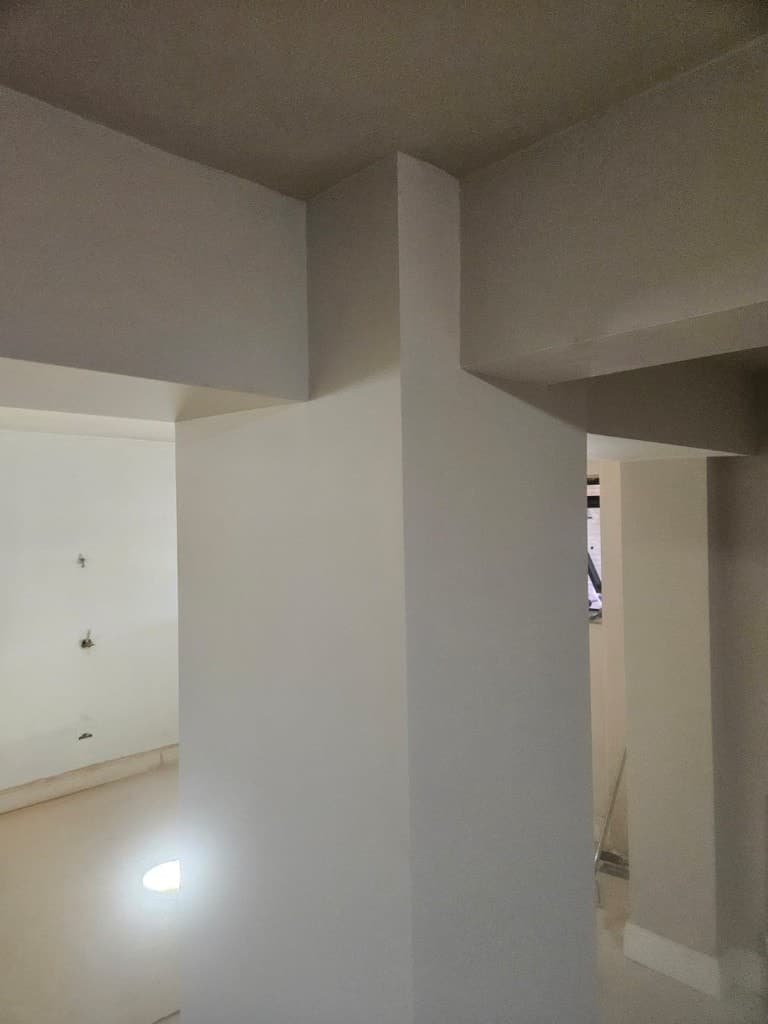 Interior painting in progress showing cream walls and ceiling bulkheads with clean lines and floor protection.